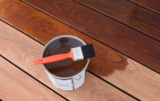 A Fijian Mahogany deck being oiled with a brush, enhancing its rich natural color and protecting it from the elements for long-lasting durability.