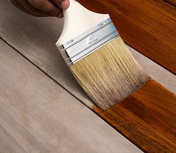 Staining Fijian Mahogany Decking for Rich Finish Close-up of a brush applying stain to Fijian Mahogany decking, enhancing its rich color and durability. This premium hardwood is perfect for long-lasting, sustainable wood decking, ideal for backyard deck ideas and outdoor spaces in Ontario, Canada.